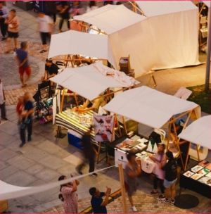 Aerial view of a busy open-air market with white canopies